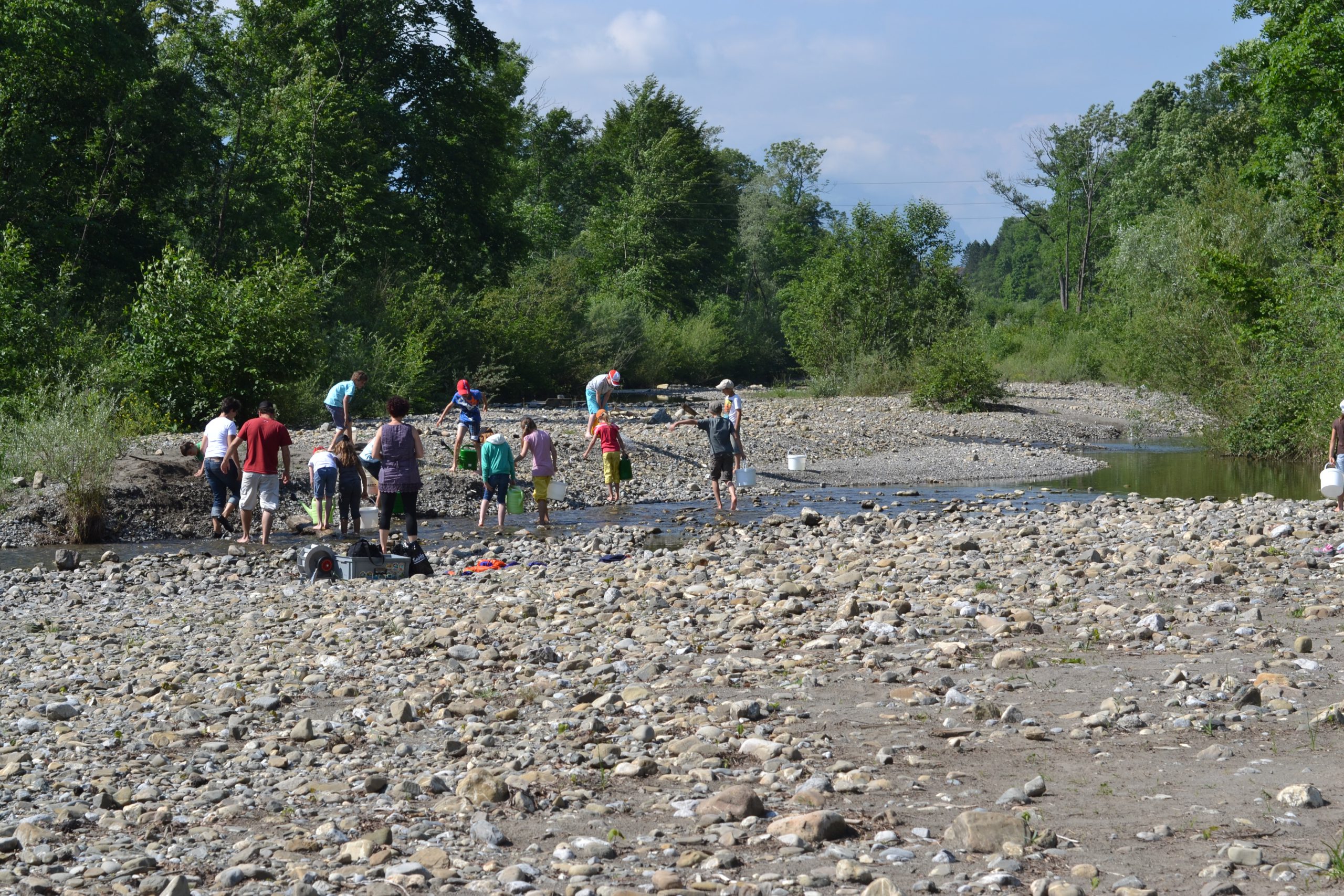 Schulkinder mit Eimern im Flussbett